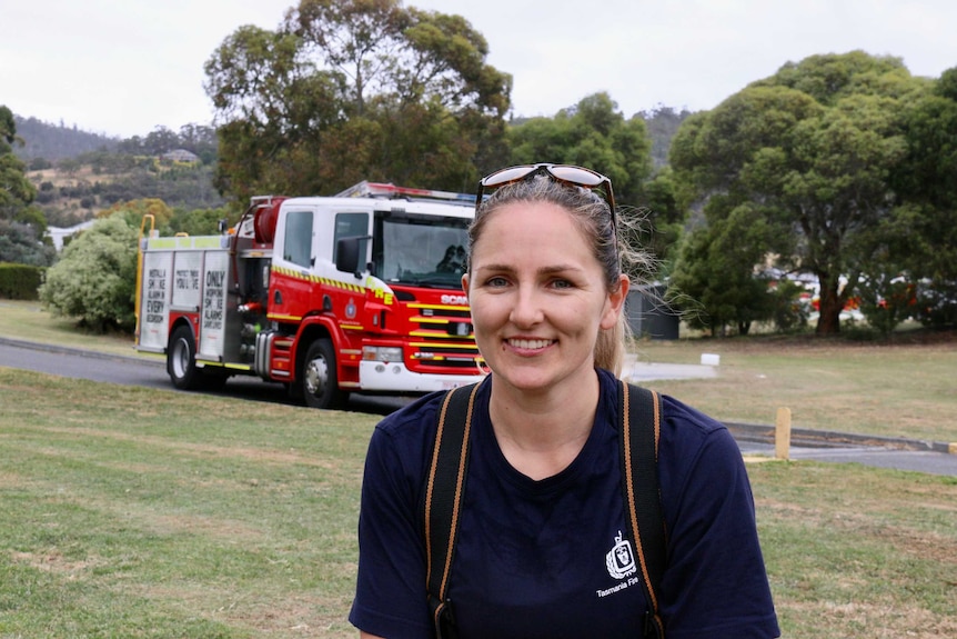 A young woman stands in front of a Tasmanian fire truck.