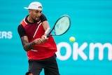 The muscles in Nick Kyrgios's neck strain as he puts all his effort into hitting a backhand return in a match. 