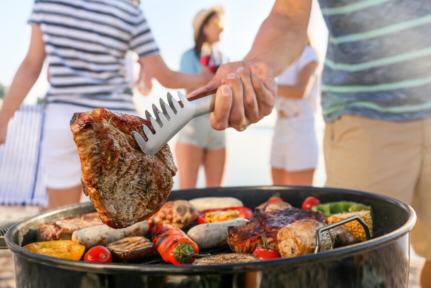 A steak being cooked on a barbecue on a sunny day.