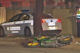 Police car and officer at the scene of an accident with a motorcycle lying on the ground.