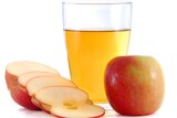 An apple sliced and a glass of apple cider vinegar