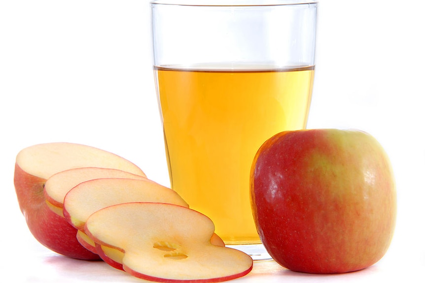 An apple sliced and a glass of apple cider vinegar