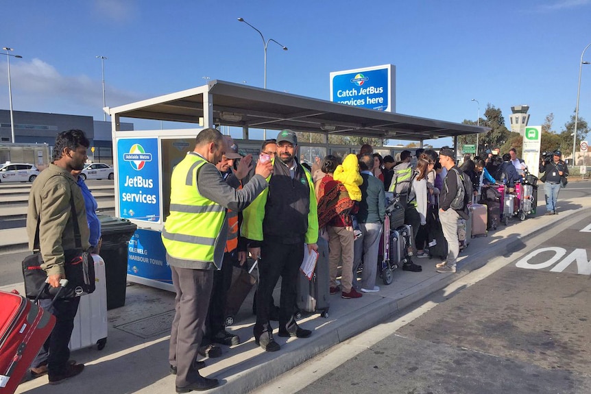 Adelaide Airport passengers at a bus stop.