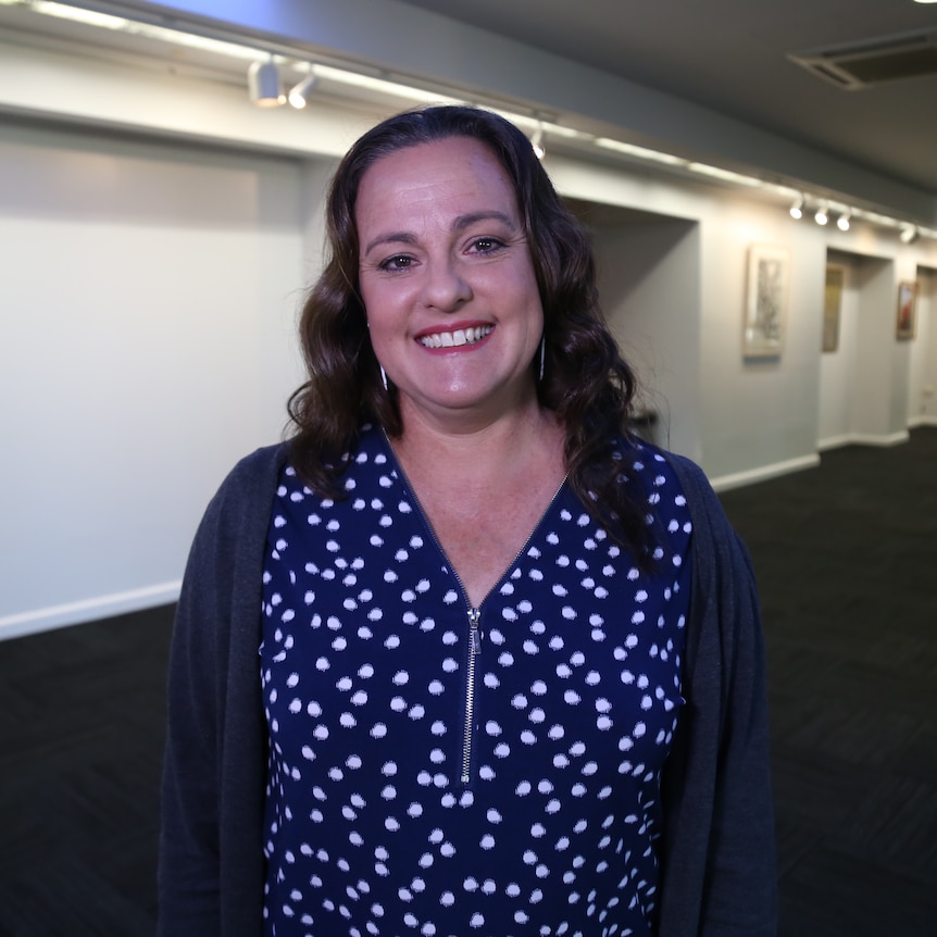 A woman stands in a room smiling