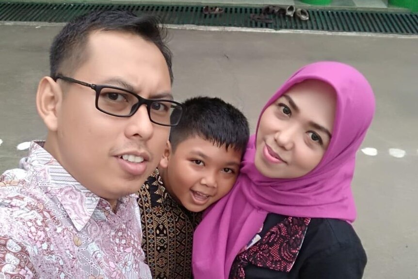 Rini Tri Utami, wearing a pink head scarf, is pictured next to her husband and two children.