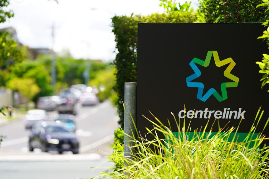 A Centrelink sign next to a busy road. 
