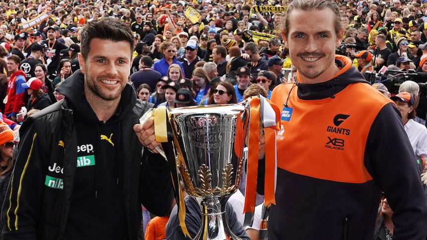 Trent Cotchin (left) and Phil Davis hold the AFL premiership cup with spectators in the background