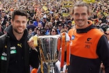 Trent Cotchin (left) and Phil Davis hold the AFL premiership cup with spectators in the background