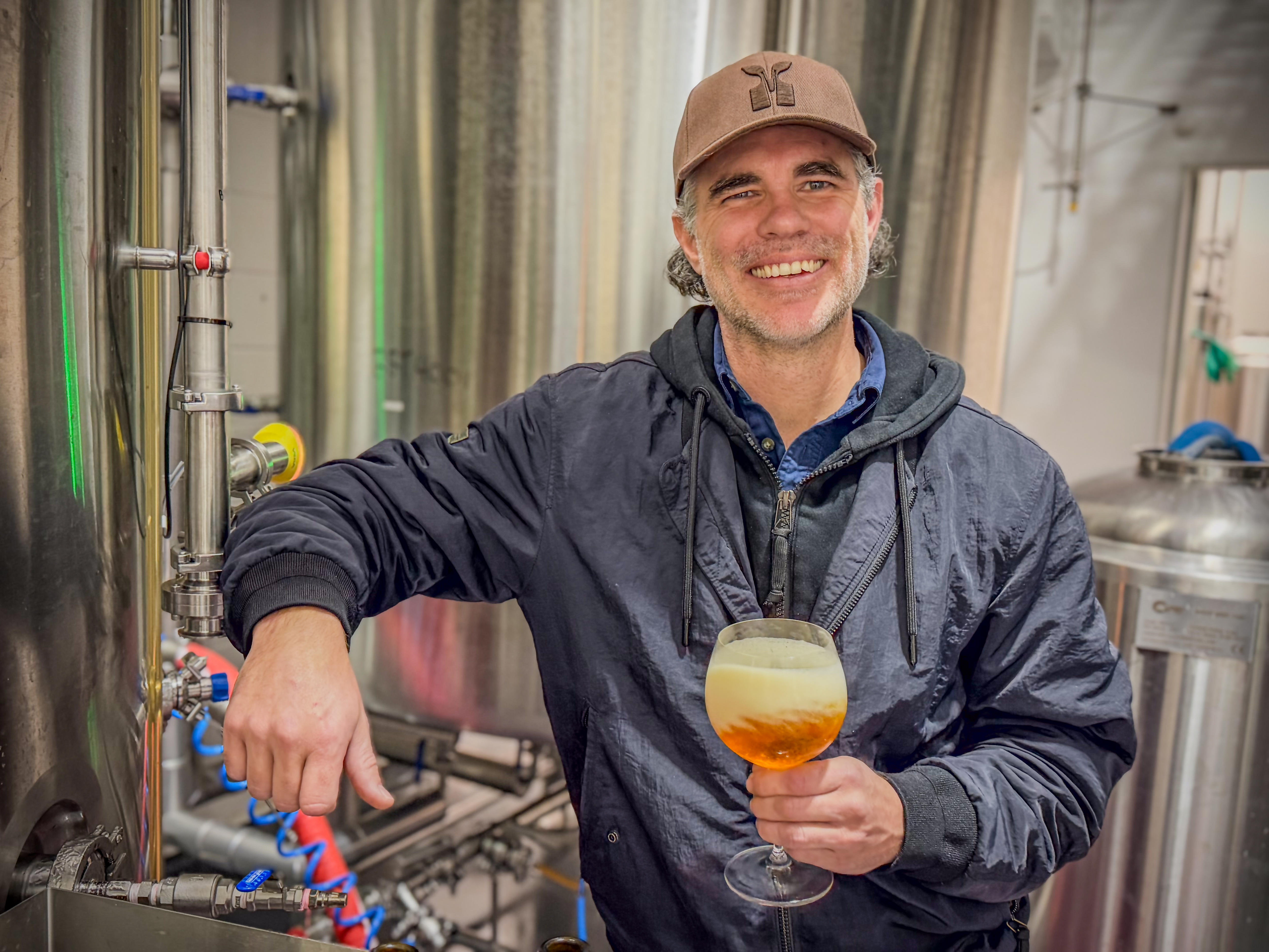 A man holding a beer in front of machinery.