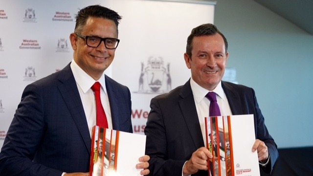 Ben Wyatt and Mark McGowan wearing broad grins and holding budget documents.