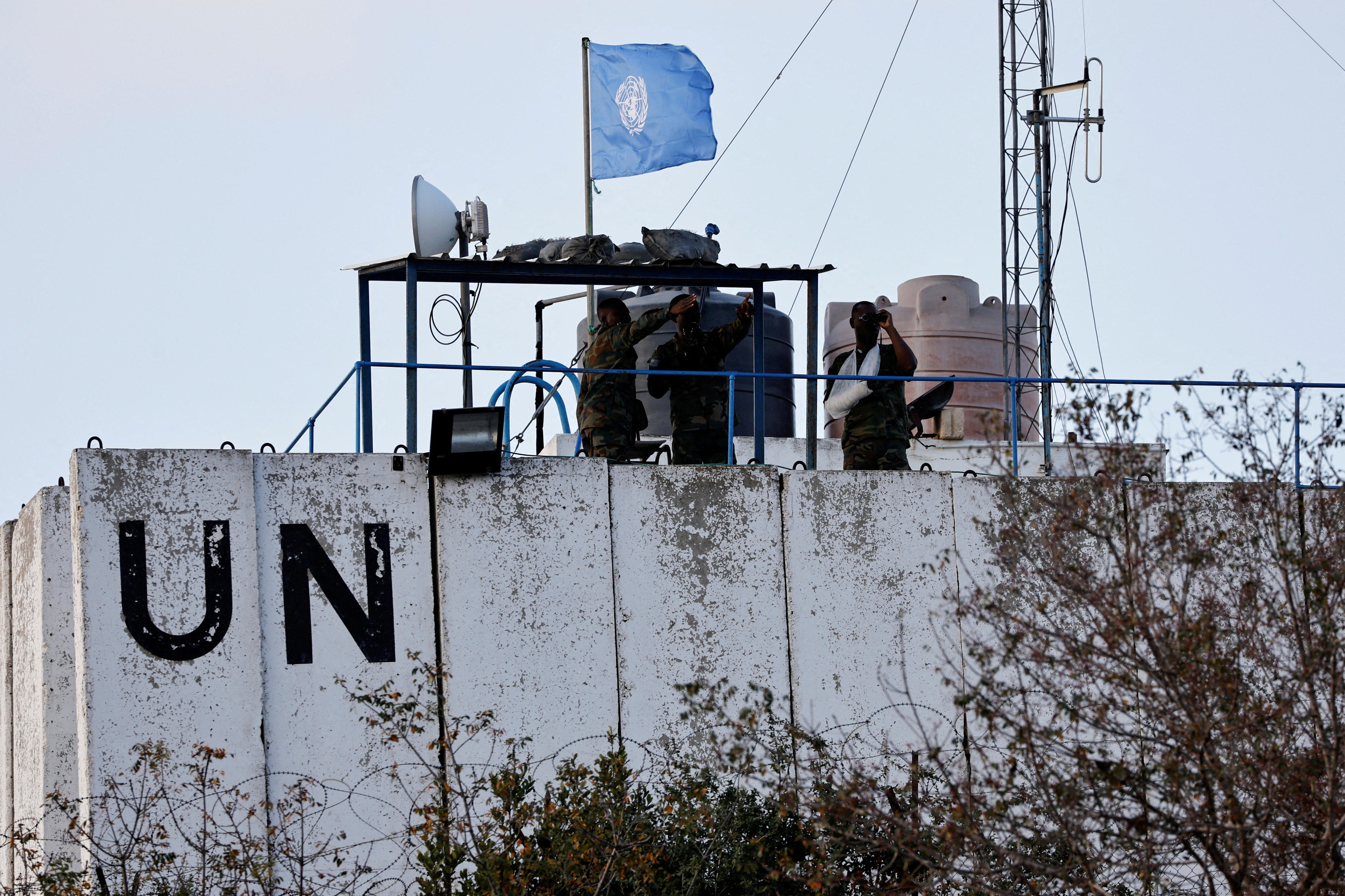 A small group of people in military uniforms look out from a watchtower.