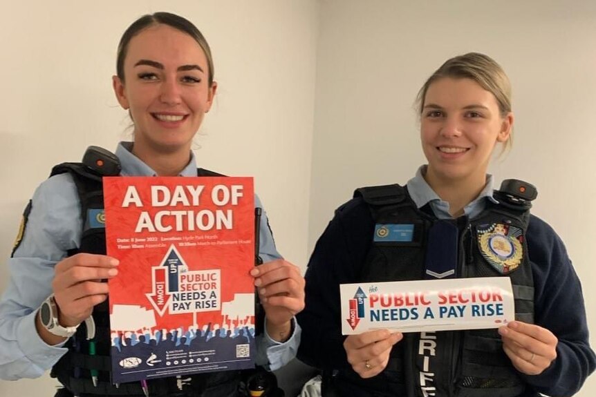 two young police women holding signs about a strike