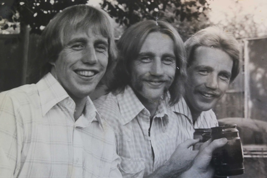 Black and white photo of three men with 70s hairstyles.