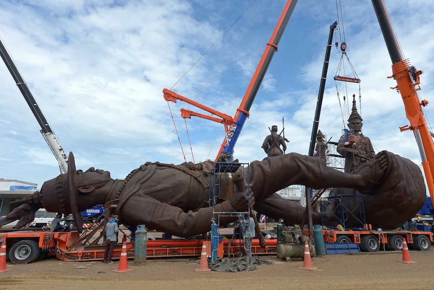 Thai workers prep and install statues of Thai kings.