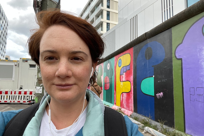 Clare Negus selfie in front of a painted wall in Berlin.