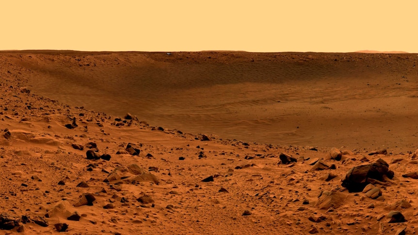 Red dirt and rock dominate this landscape of Mars, and the sky is a light orange