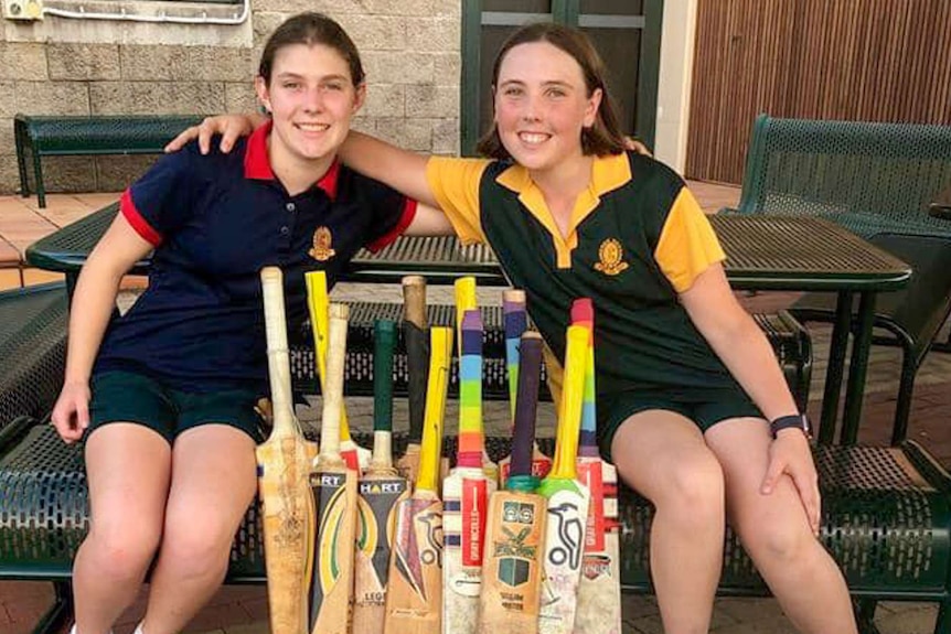 Two female cricket players with bats and balls.