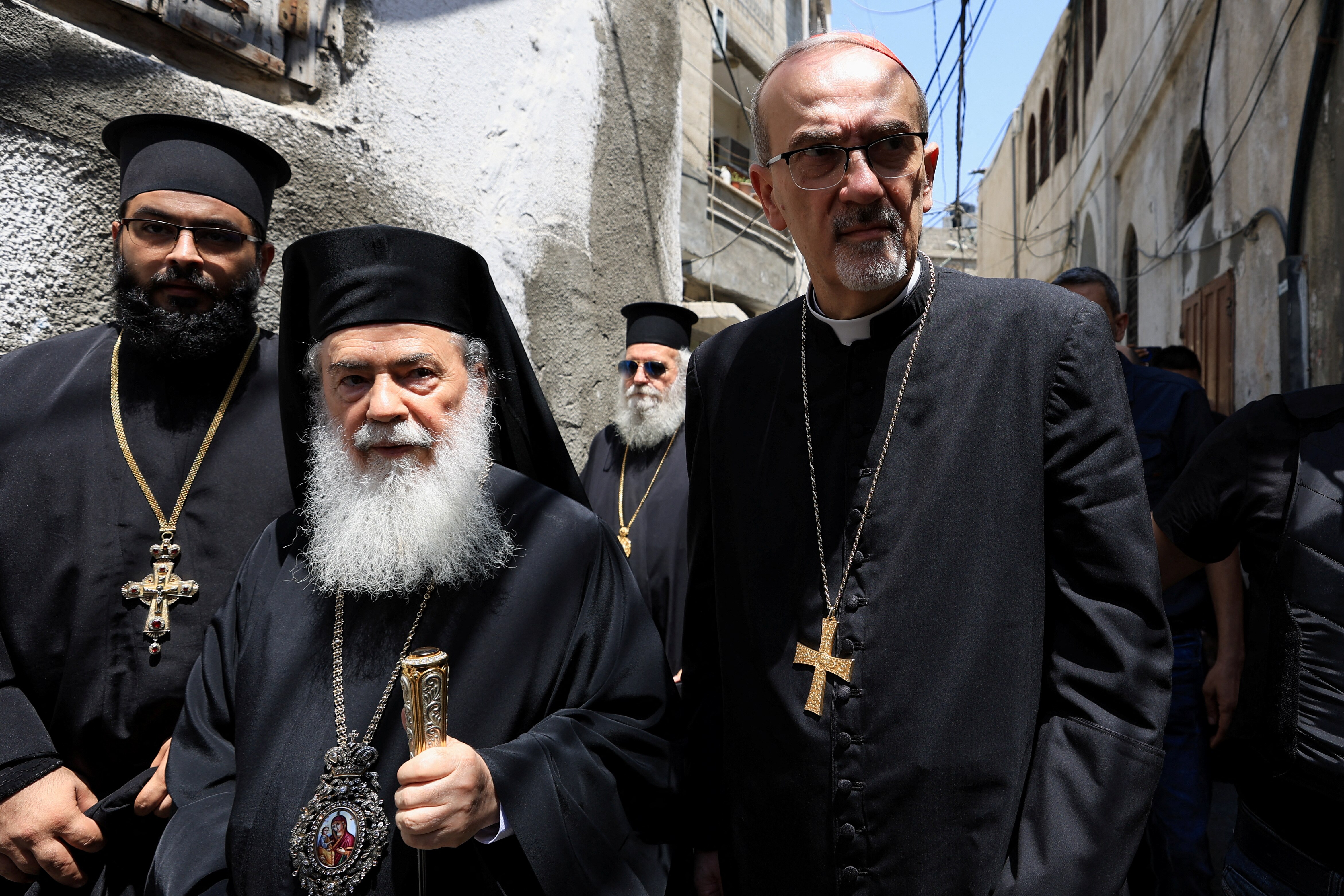 Three men in black robes wearing crosses and religious jewellery. 