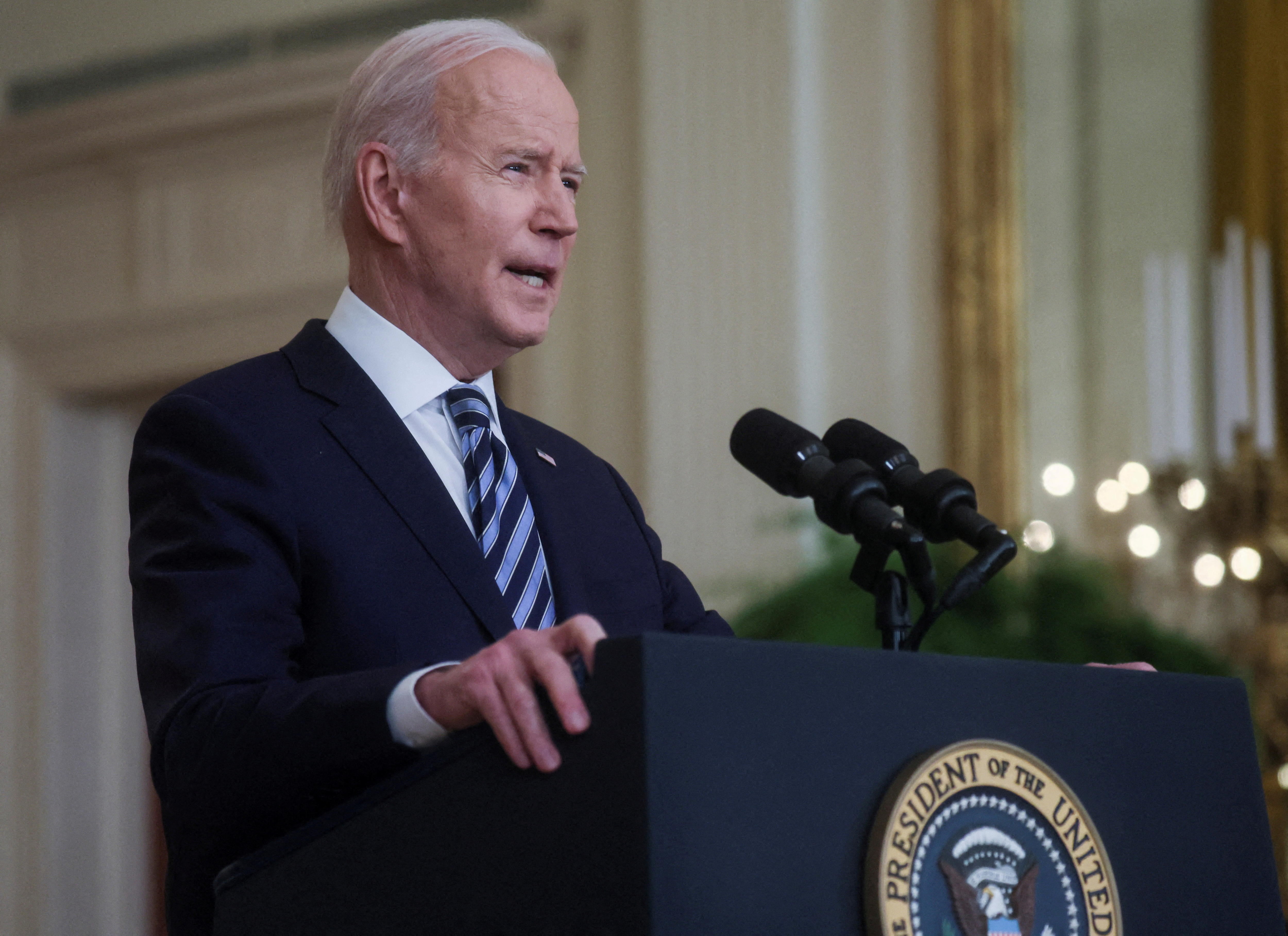 Joe Biden speaks into a microphone at a lectern with a US presidential seal on the front