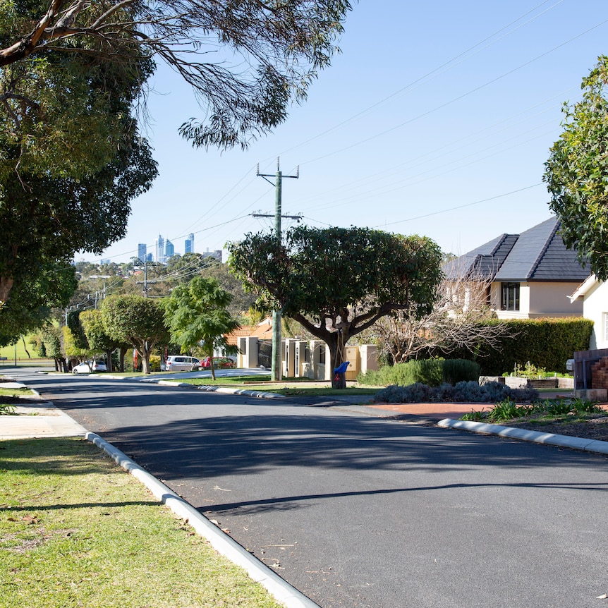 A view of the Perth city skyline from a suburban street lined with houses and trees