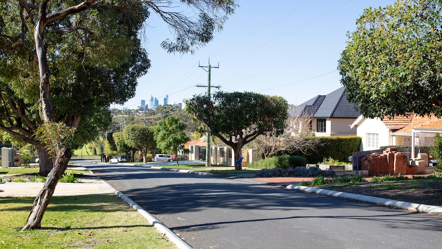 A view of the Perth city skyline from a suburban street lined with houses and trees