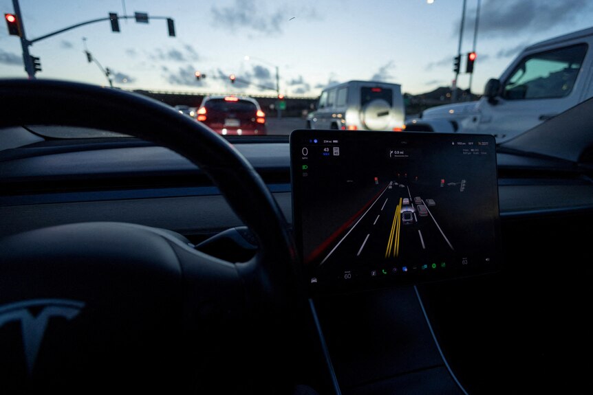 An image taken inside a Tesla Model 3 which is running Autopilot showing the steering wheel, screen and windscreen