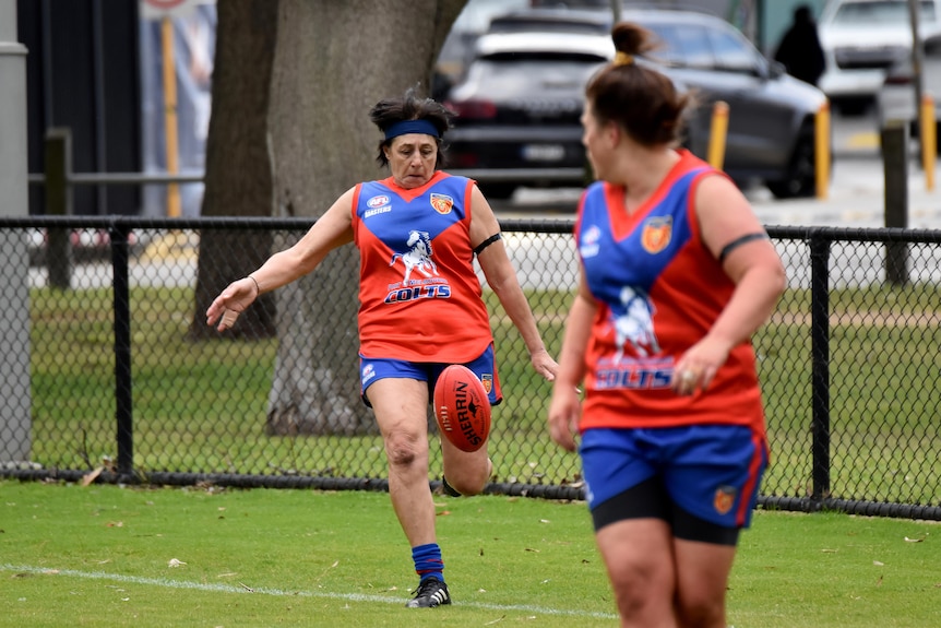 Player Michelle Lewis in the motion of kicking the ball.