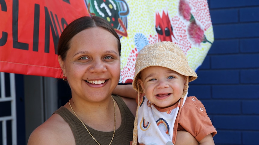 A young woman holds a baby in her arms