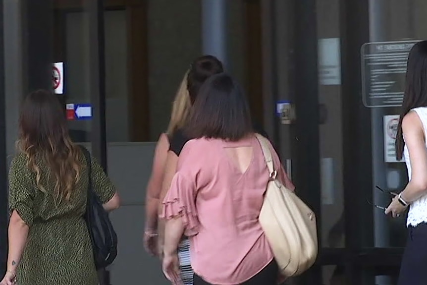 Five women seen from behind entering a court building