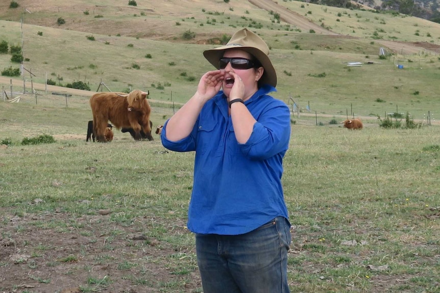 Bec Lynd stands in the paddock among the Scottish Highland cattle.