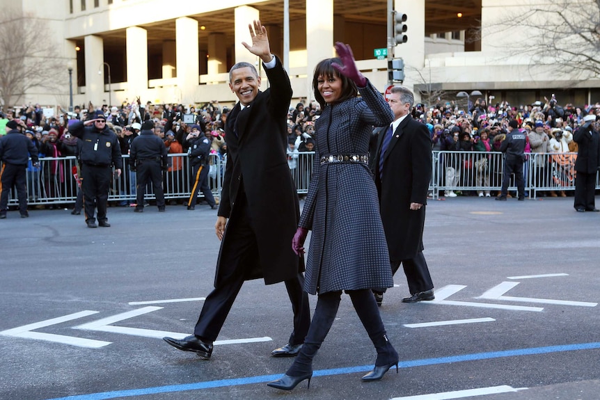 Barack and Michelle Obama walk along Pennsylvania Avenue.