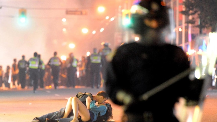 A Perth couple kiss amid violent protest scenes in Vancouver