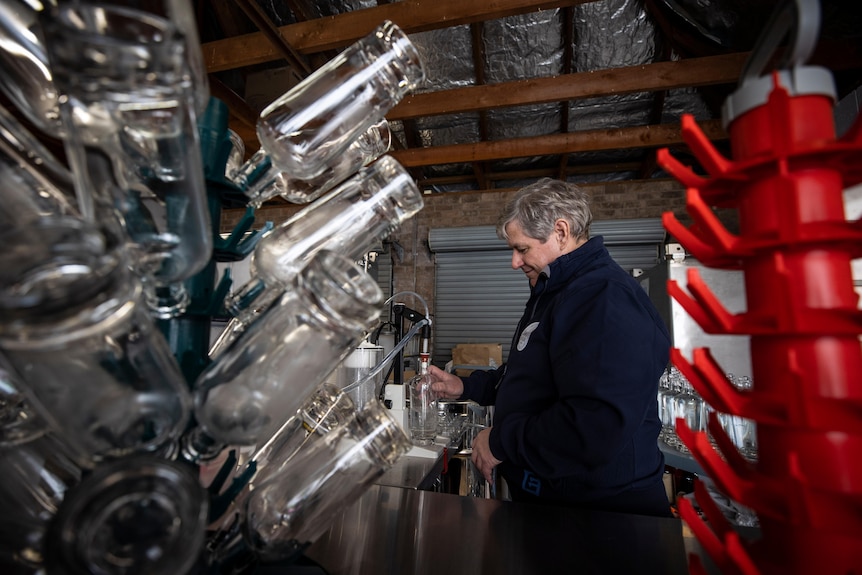 A man fills a bottle with lots of bottles in the foreground