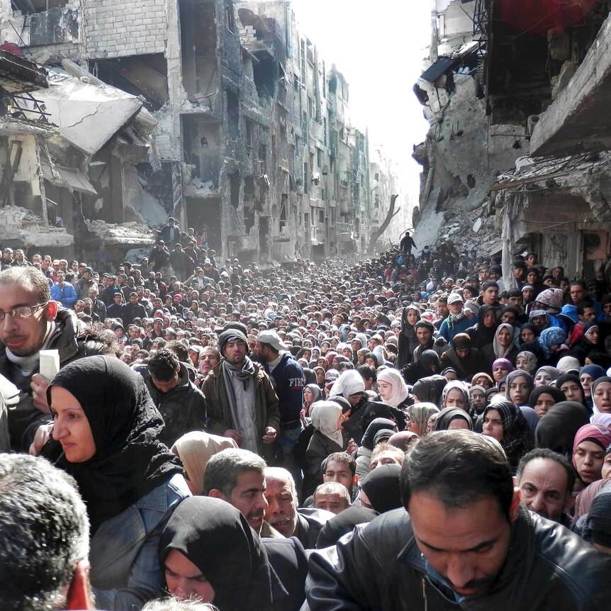 Thousands of Palestinian refugees cue for food supplies in ruins of Damascus