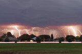Multiple lightning strikes over an oval and houses