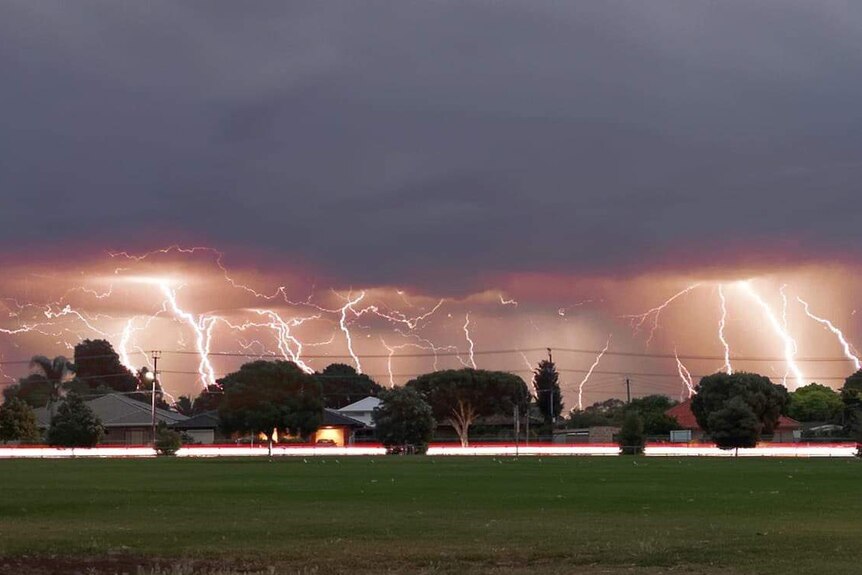 Multiple lightning strikes over an oval and houses