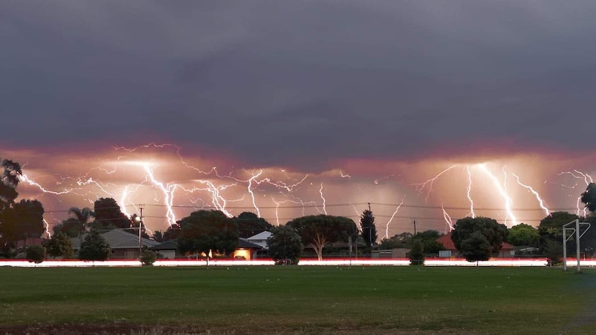 Multiple lightning strikes over an oval and houses