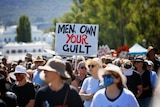 A sea of female protestors with a sign that reads "Men, own your guilt"