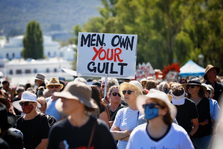 A sea of female protestors with a sign that reads "Men, own your guilt"