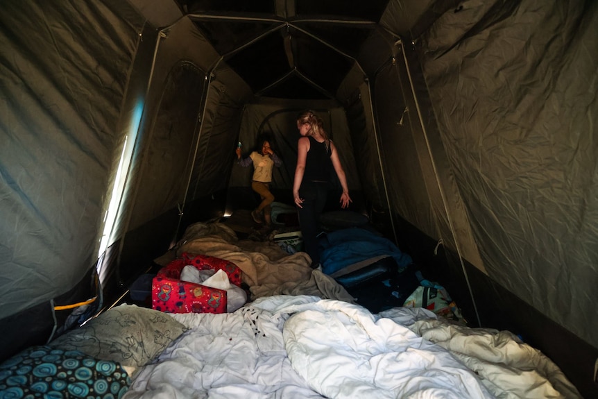 Two girls inside a large tent that is their home.