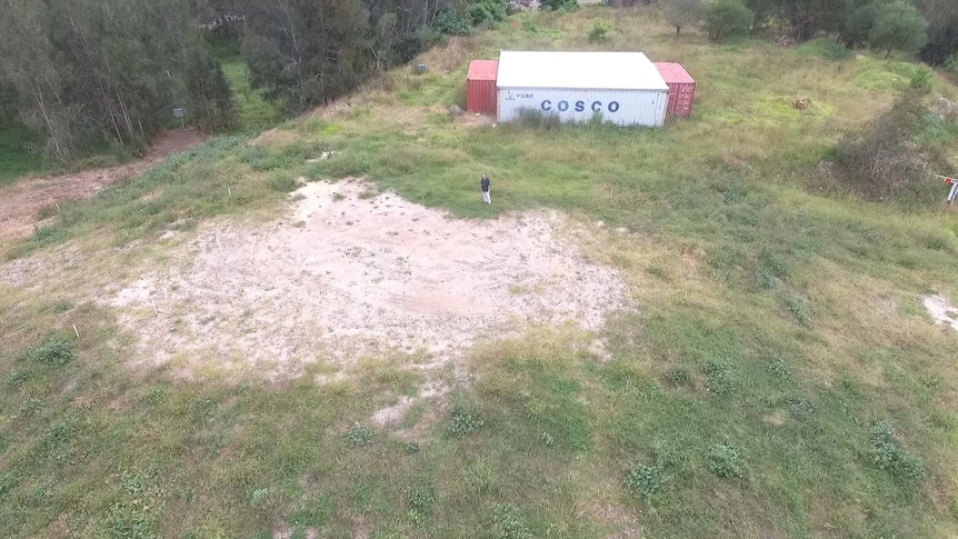 A drone shot above a property with a flood mound and shipping container.
