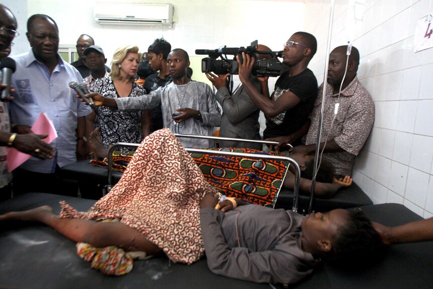 Alassane Ouattara and wife, Dominique, visit a stampede victim in hospital.