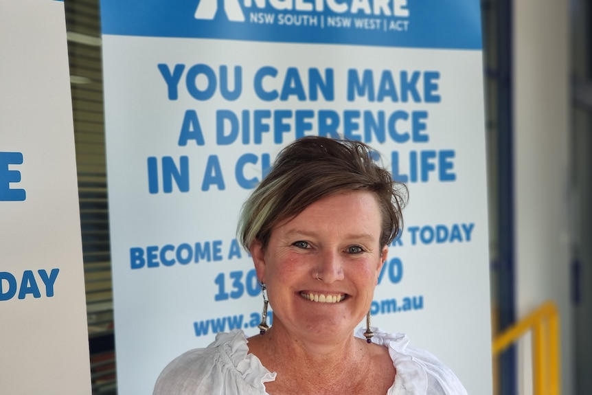 Albury Anglicare Manager Melanie Reid stands in front of a Anglicare make a difference in a child's life banner