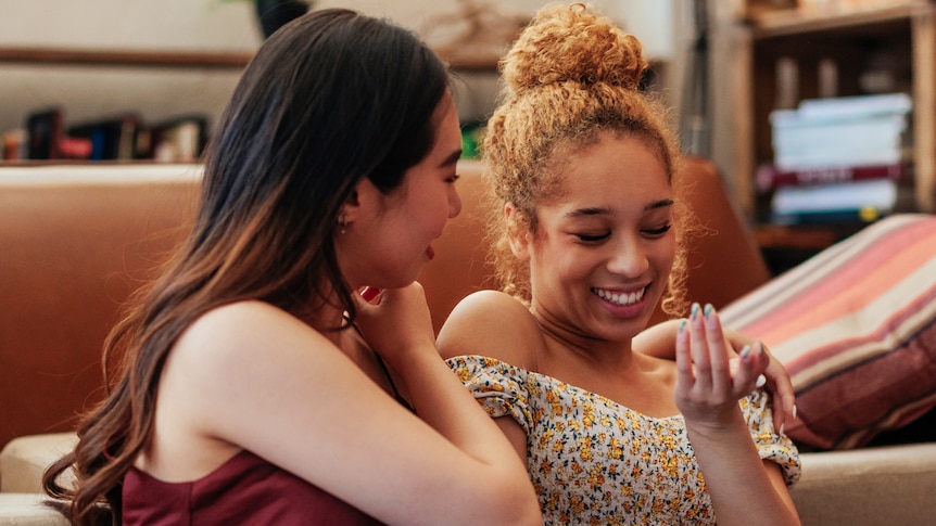 two women laughing with each other in the living room