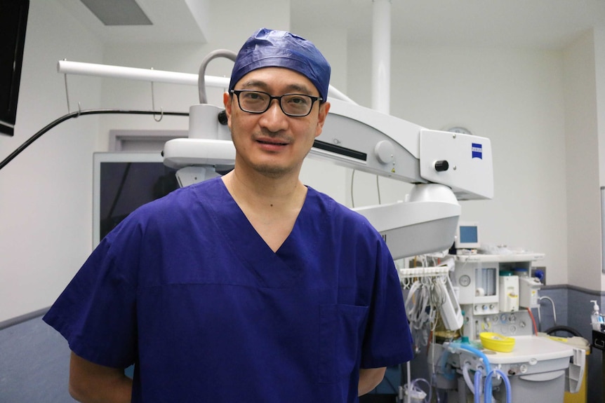 Doctor with glasses standing in front of medical equipment in a surgery room