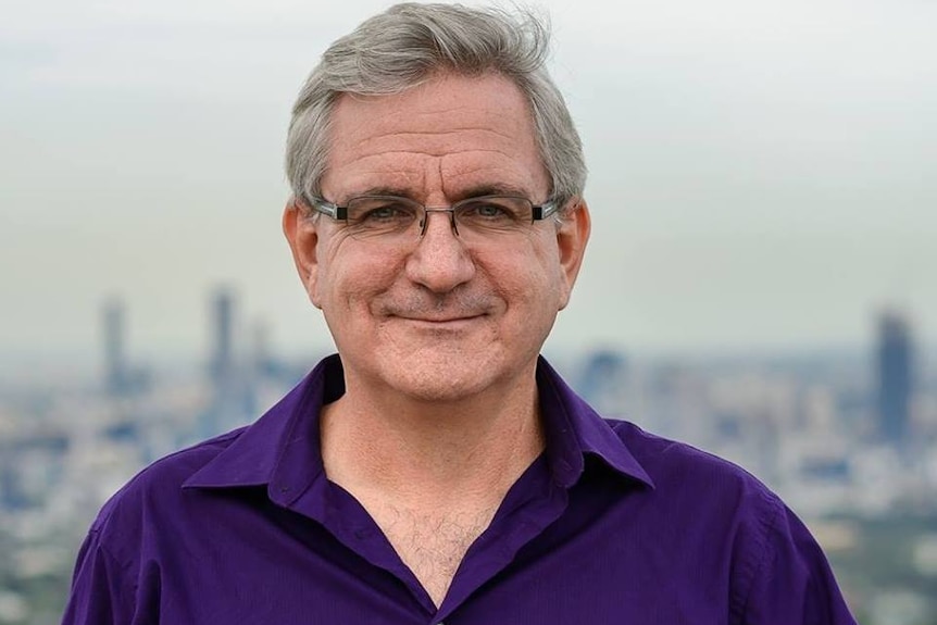 Portrait of former senator Andrew Bartlett with Brisbane skyline in background.