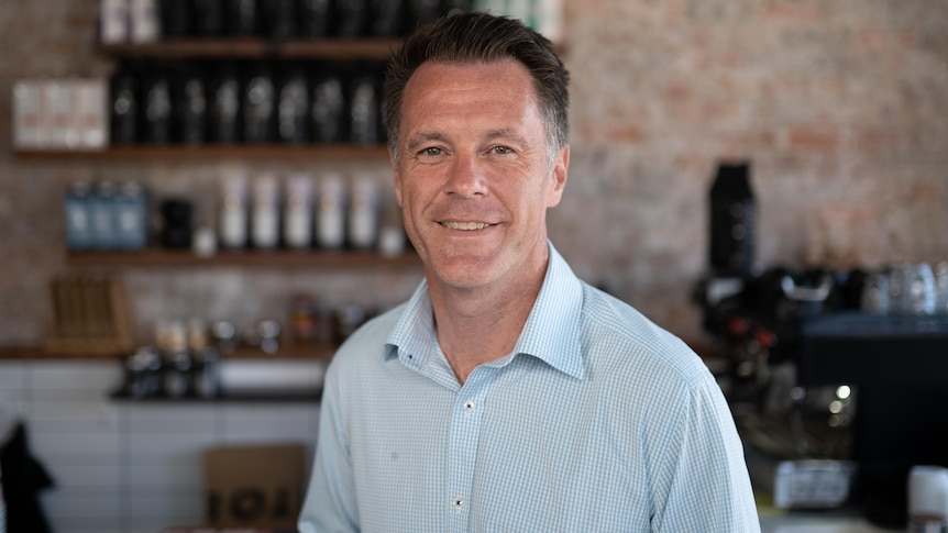 a man standing in a cafe looking at the camera and smiling