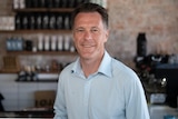 a man standing in a cafe looking at the camera and smiling