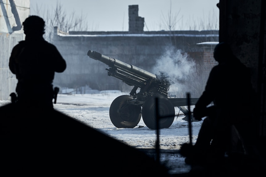 Soldiers fire a small howitzer cannon.