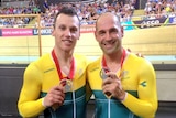 Two men standing in cycling uniforms holding up silver medals